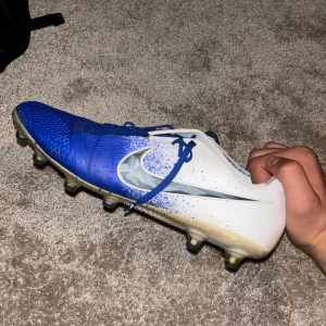 Nike Phantom Venom storlek 45 - Säljer ett par Nike Phantom Venom fotbollsskor som jag köpte för ett tag sedan men som tyvärr inte passade min fot riktigt. Skorna har snörning och mönstrad ovandel för extra grepp på planen. Perfekta för dig som vill sticka ut på fotbollsplanen! Vill gärna bli av med dom rätt snabbt så säljer billigt vid snabb affär!!