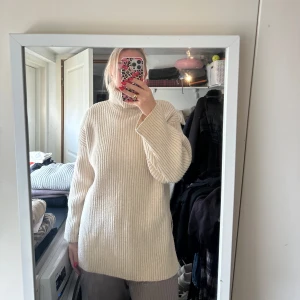 Beige ribbstickad polotröja - Säljer en beige ribbstickad polotröja med lång ärm och hög krage. Tröjan har en lös passform och slits i sidorna, perfekt för lager-på-lager. Supermjuk och skön att bära.