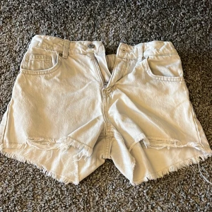  jeansshorts med fransar från Zara - Säljer ett par  jeansshorts från Zara med råa fransade kanter och klassisk femficksdesign. Shortsen har normal passform och stängs med knapp och dragkedja. Perfekta för sommaren!