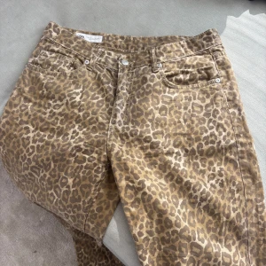 Leopardmönstrade jeans från Zara - Säljer ett par snygga jeans från Zara med leopardmönster i beige och bruna toner. Byxorna har klassisk femficksmodell, normal passform och stängs med dragkedja och knapp. Vida i benen och mycket långa. Jag bär vanligtvis 38 i jeans och är 180cm lång. Tveka inte på att ställa frågor eller skicka prisförslag!