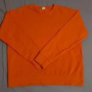 Orange sweatshirt i bomull - Säljer en enkel och stilren orange sweatshirt i mjuk bomull. Tröjan har rund halsringning och långa ärmar. Perfekt för dig som gillar färg och vill ha en bekväm tröja till vardagen.