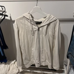 Vit hoodie med dragkedja - Säljer en vit hoodie  med dragkedja framtill och huva. Tröjan har fickor på magen och långa ärmar. Perfekt för en avslappnad stil och enkel att matcha med jeans eller mjukisbyxor.