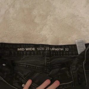 Svarta mid wide jeans - Säljer ett par svarta jeans med midja i midwaist-modell och wide passform. Jeansen har klassisk femficksdesign och raka ben. Perfekta för en avslappnad och trendig look.