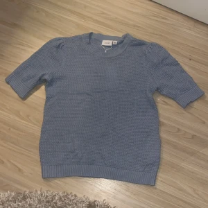 Ljusblå Stickad T-Shirt - Super fin stickad T-shirt. Helt ny med prislappen på. Den är en ljusare blå i verkligheten. Skriv gärna om du har frågor!🤍