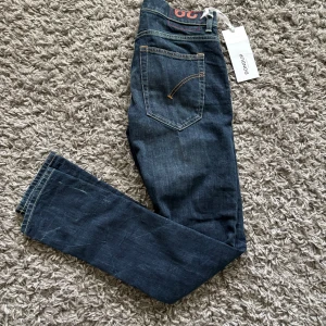 Mörkblå jeansbyxor från Dondup i storlek W29 L32 - Säljer ett par mörkblå jeansbyxor från Dondup med klassisk femficksdesign och kontrastsömmar. Byxorna har rak passform och normal midja, samt en diskret logga baktill i midjan. Perfekta för en stilren look.