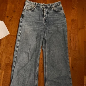 Blå wide jeans från never denim - Säljer ett par blå jeans från never denim med breda ben och klassisk femficksdesign. Jeansen har hög midja och raka, vida ben för en avslappnad look. Perfekta till sneakers eller boots.