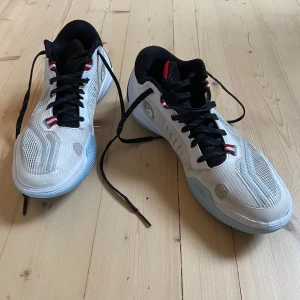 Basketskor ”Way of Wade ice blood 2” - Säljer ett par vita Way of Wade basketskor med svarta och röda detaljer. Skorna har snörning, svart insida och en färgglad sula undertill. Ovandelen är i syntetmaterial med mesh för extra ventilation. Perfekta för dig som gillar basket.
