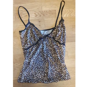 Leopardmönstrad linnetopp från Green Coast - Säljer en y2k leopardmönstrad linnetopp från Green Coast i Portugal i storlek 42 (passar S/M) Toppen har tunna axelband och svarta spetsdetaljer vid bysten. Perfekt för dig som gillar leopardmönstrad. Toppen har en textur.
