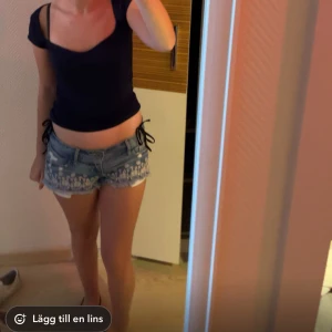 Hollister jeans shorts lågmidjade  - Säljer ett par blå jeansshorts med vita broderade blommor och råa kanter. Shortsen har normal passform och är lågmidjade. Perfekta för sommaren!