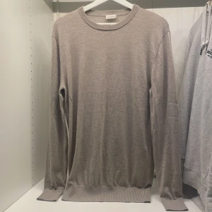 Beige stickad tröja från John Henric - Säljer en stilren beige stickad tröja från John Henric i storlek M. Tröjan har rund halsringning, perfekt för lager-på-lager eller som den är. Enkel och klassisk design som passar till mycket.