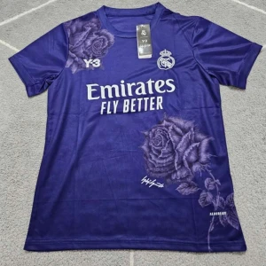 Lila - Real Madrid fotbollströja  - Snygg lila Real Madrid fotbollströja i samarbete med Y-3. Tröjan har vita tryck med klubbmärke, sponsor och Y-3-logga samt stora ros-motiv på både fram- och baksidan. Tillverkad i ett lätt och svalt material, perfekt för match eller träning. Vid frågor är det bara att kontakta 