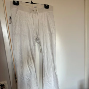 Vita byxor från Juicy Couture - Säljer ett par vita  byxor från Juicy Couture. Köpta från Sellpy. Har en fläck på benet och knapparna är slitna 