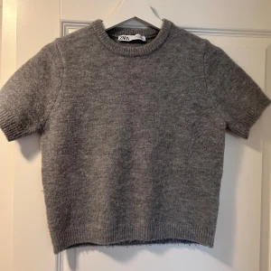 Grå stickad kortärmad tröja från Zara - Mysig grå stickad tröja från Zara med korta ärmar. Den är använd ca 4 gånger, så den är i bra skick.