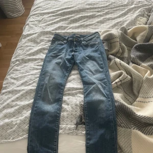 Blå slim fit jeans Glenn - Säljer ett par blå slim fit jeans, modell Glenn. Klassisk femficksdesign med dragkedja och knapp. Jeansen har en smal passform och är perfekta för dig som gillar en modern look. Midjan är normal och materialet är klassisk denim. Hör av dig vid minsta fundering!