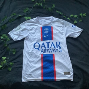 PSG Neymar Jr 10 fotbollströja - Säljer en vit PSG fotbollströja med Neymar Jr och nummer 10 på ryggen. Tröjan har blå och röda vertikala ränder på framsidan, Qatar Airways som sponsor och klubbmärke på bröstet. Kortärmad modell med klassisk passform.