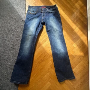 Mörkblå vintage low waist jeans - Lågmidjade jeans från Blend med klassisk femficksdesign och dubbla knappar i midjan. Jeansen är lowwaist och blekta på benen. Innerbenslängd: 80 cm Waist: 41 cm
