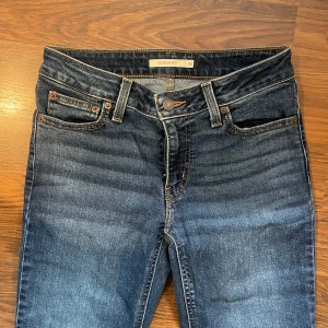 Levis jeans - Levis jeans i mörkblå tvätt med låg midja, vida ben och fem fickor. Byxorna har knappgylf och tydliga kontrastsömmar. Perfekta för dig som gillar tidlös denimstil.