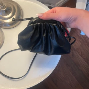 Clutch bag - Säljer en svart lime clutch bag i skinnimitation med dragskostängning. Väskan har en mjuk, rynkad design och en smal axelrem. Perfekt för att bära det viktigaste när du är på språng.