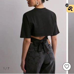 Svart croppad topp med knytband - Snygg svart croppad topp med knytband i ryggen. Toppen har korta ärmar och en stilren design som passar perfekt till både jeans och kjol. Perfekt för en trendig look! 