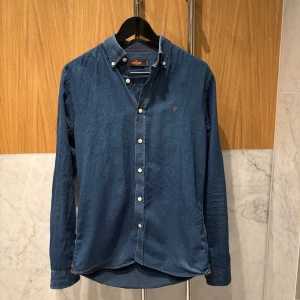 Blå jeansskjorta från Morris - Snygg blå jeansskjorta från Morris med broderad detalj på bröstet i storlek S/38,  perfekt nu till våren! 