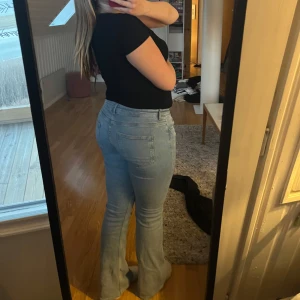 Ljusblå bootcut jeans - Snygga ljusblå bootcut jeans med medelhög midja. Perfekta för en avslappnad stil. Klassisk femficksdesign och dragkedja framtill.