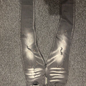 Svarta jeans från Dsquared2 - Snygga svarta jeans från Dsquared2 med slitna detaljer och färgstänk i orange och vitt. De har en klassisk femficksdesign och en knappgylf. Perfekta för en trendig look. Hör av er vid minsta fundering 🍾