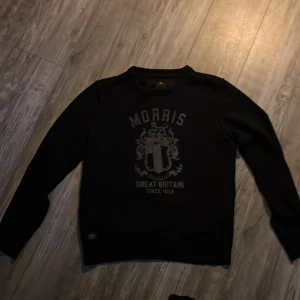 Svart tröja från Morris - Snygg svart tröja från Morris med tryck framtill. Perfekt för en stilren look. Tröjan har långa ärmar och rund halsringning.