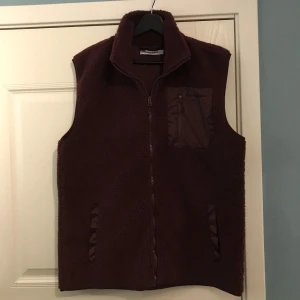 Vinröd fleeceväst från Frank Dandy - Säljer en vinröd fleeceväst från Frank Dandy med dragkedja och en praktisk bröstficka. Perfekt nu inför våren. Helt ny med tags kvar!