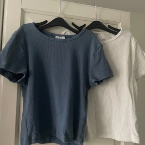 Ribbad topp i blått och vitt - Två ribbade toppar i blått och vitt med korta ärmar i storlek XS. Perfekta för en avslappnad stil. De har en rund halsringning och är tillverkade i ett mjukt material. Använda endast ett fåtal gånger! Skriv för fler bilder💗