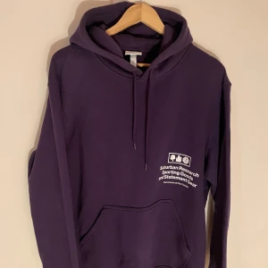 Lila hoodie från H&M - Säljer en rare oanvänd lila hoodie från H&M i storlek M med tryck på framsidan. Den har en klassisk känguruficka och justerbar huva. Perfekt för en avslappnad stil.