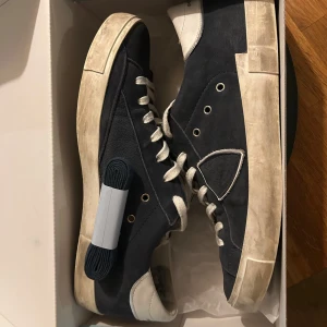 Phillipe Model - Ett par navy phillipe model i riktigt bra skick, de är inga defekter på skorna. Köpta på kicksnstuff. Med skorna skickas de med org kartong och extra snören i mörkblå färg. Kvitto finns. De är små i storleken så skulle säga att de passar som ett par 43:or. För fler frågor är det bara och skriva☺️