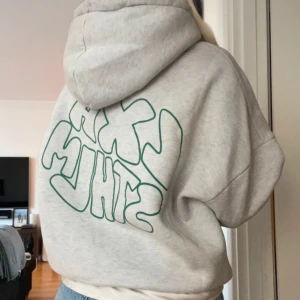 Grå hoodie med tryck - Säljer nu min grå LXA  hoodie med ett stort grönt tryck på ryggen. LXA. Den har en bekväm passform och en klassisk huva. Perfekt för en avslappnad stil.