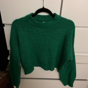 Grön stickad tröja från Ivy Trend - Säljer en snygg grön stickad tröja från Ivy Trend. Tröjan har en croppad design och långa ärmar, perfekt för kyligare dagar. Den är i storlek XS och har en ribbad struktur som ger en stilren look. Passar perfekt till jeans eller kjol för en avslappnad stil.