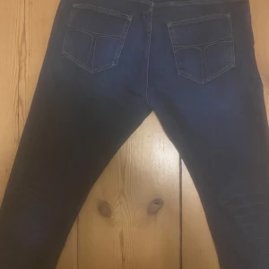 Mörkblå jeans från Tiger of Sweden - Snygga mörkblå jeans från Tiger of Sweden med klassisk femficksdesign. Perfekta för en stilren look. Tillverkade i högkvalitativt material för en bekväm passform.