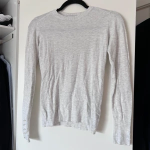Ljusgrå stickad tröja från Zara - Säljer en ljusgrå tunn stickad tröja från Zara med långa ärmar och fina pärldetaljer vid ärmsluten. Perfekt för en stilren och bekväm look. Tröjan har en rund halsringning och är i en mjuk och skön kvalitet. Mycket sparsamt använd 🤍 Önskar du veta exakta mått? Tveka inte att höra av dig!