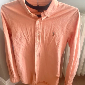 Skjorta | Ralph lauren  - Ralph lauren | Oxford Skjorta | Aprikos färg Orange/Rosa (ny färg hos ralph lauren) | Stl S/M | 🚨 Passa på att införskaffa denna till sommaren, innan efterfrågan skenar iväg 🚨| Modellen är 185 cm & 72 kg | Nypris 1645:- ⚠️ Mitt pris 419:- ⚠️ 
