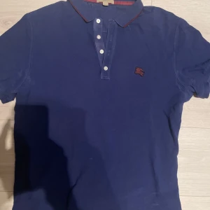 Burberry Piké - En riktigt schysst piké från burberry som tyvärr blivit för liten för mig nu. En riktigt snygg blå färg och väldigt bra skick. Pris diskuterbart!