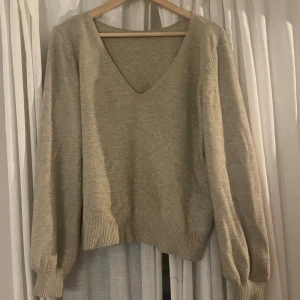 Beige stickad tröja med v-ringning - Säljer en supermysig beige stickad tröja med v-ringning. Den har långa ärmar och ribbade muddar vid ärmslut och nederkant. Perfekt för höst och vinter när du vill hålla dig varm och stilren. Passar till både jeans och kjol!