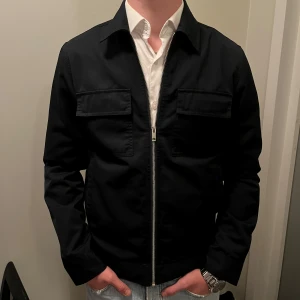 Elvine Jacka Mörkblå - Tvärsnygg höst/vår-jacka från det svenska märket Elvine.  I nyskick. Endast använd ett fåtal gånger. Storlek M. Något liten i storleken. Nypris ca 2300.   Tveka inte på att ställa frågor eller be om fler bilder så löser vi det. 