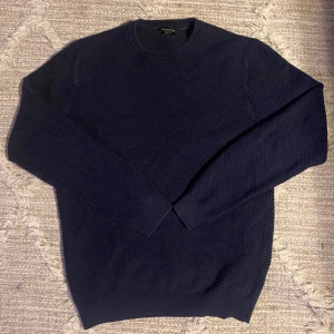 Mörkblå tröja från Massimo Dutti - Snygg mörkblå tröja från Massimo Dutti i en mjuk blandning av bomull och kashmir. Tröjan har en diskret textur och rund halsringning, perfekt för kyligare dagar. Den är i fint skick och priset kan diskuteras.