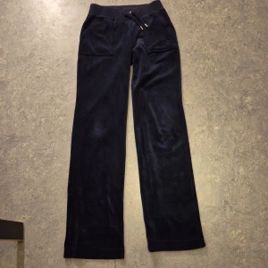 Mörkblå mjukisbyxor med snörning - Snygga mörkblå mjukisbyxor i mjukt material med snörning i midjan. Byxorna har fickor både fram och bak, med dekorativa knappar på bakfickorna. Perfekta för en avslappnad stil. Köpta för 1100 kr