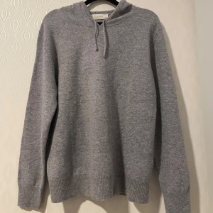 Grå kashmir hoodie från Sayless - Säljer en supermjuk och stilren grå hoodie i kashmir från Sayless. Perfekt för kyliga dagar med sin bekväma passform och klassiska design. Den har en justerbar huva och ribbade muddar för extra komfort. SISTA PRIS 750kr.