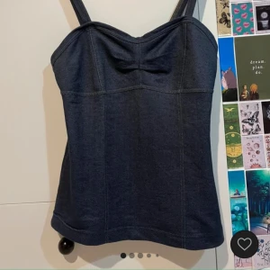 Mörkblå korsettlinne - Snygg mörkblå korsettlinne med breda axelband och en subtil knytdetalj framtill. Perfekt för en stilren och elegant look.