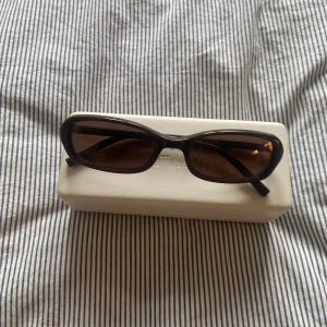 Bruna solglasögon från CHIMI - Snygga bruna solglasögon från CHIMI med en elegant rektangulär form. De har en stilren design och kommer med ett vitt fodral. Perfekta för att ge en trendig touch till din outfit. Typ: Code Brown