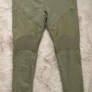 Gröna leggings från Gymshark - Snygga gröna leggings från Gymshark i storlek M. Tillverkade i ett stretchigt material med texturerade paneler för extra stil. Perfekta för träning eller en aktiv vardag.