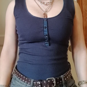 Mörkblå ribbad linnetopp - Snygg mörkblå ribbad linnetopp med knappar framtill. Perfekt för en casual look. Toppen är ärmlös och har en tight passform.