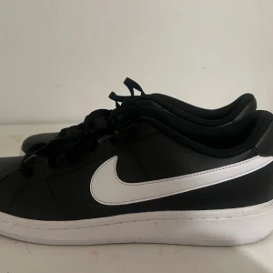 Herr Nike Sneaker Court Royale 2 Low - Snygga svarta Nike sneakers med. Skorna har klassisk snörning och en bekväm passform, perfekt för vardagsbruk. Skorna är också väldig nya eftersom dem inte har används mer än 3  gånger ute. Skorna passar inte användaren längre och det e dags för dessa skor att få en hem. 