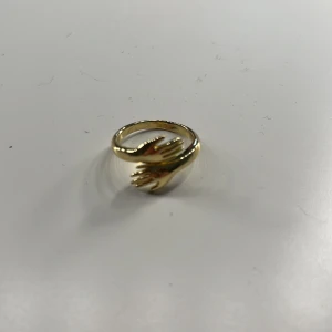 En jättevacker ring💞❤️ - Elegant guldfärgad ring med unik design av två händer som omsluter fingret. Perfekt för att ge en personlig touch till din stil. Passar både till vardag och speciella tillfällen.