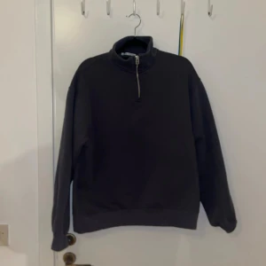 Mörkgrå tröja med dragkedja från Zara - Säljer en stilren mörkgrå tröja med halv dragkedja och hög krage. Perfekt för kyligare dagar. Tröjan har långa ärmar och en avslappnad passform.