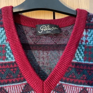 Mönstrad stickad väst från Peluso - Snygg stickad väst från Peluso i ett färgglatt mönster med rött, blått och svart. Västen har en v-ringad design och är perfekt för att lägga till lite retrostil till din outfit.